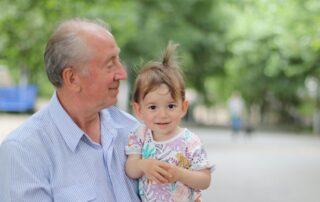 Grandfather holding his young grandchild in a sunny park